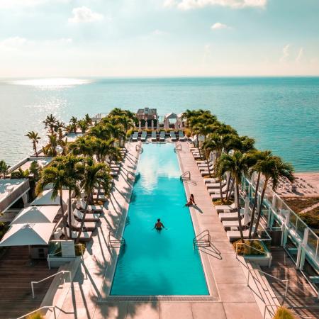 pool surrounded by palm trees next to a beach