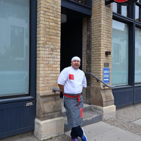 Sushi chef standing in front of restaurant.