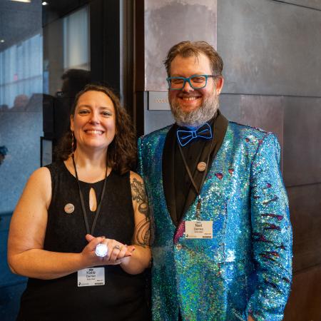 a woman and man in fancy attire looking at the camera, smiling.