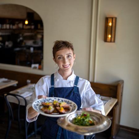 photo of a female chef holding plates of food