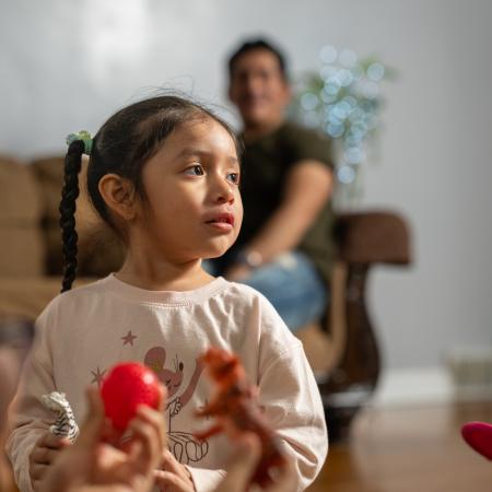 Little girl with pigtails, playing with toys on the floor of her living room.