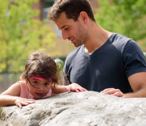 A parent next to a child on a rock