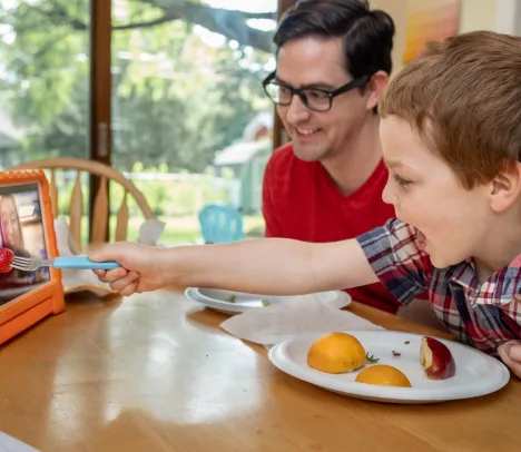 A child at a dining table interacting with a tablet