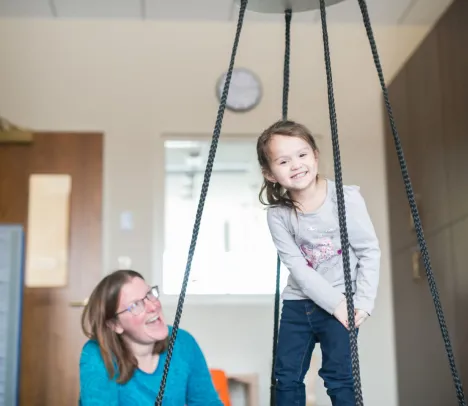 A child smiling and balancing with ropes