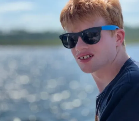 A teenager with sun glasses looking at the camera