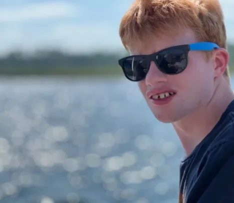 A teenager with sun glasses looking at the camera