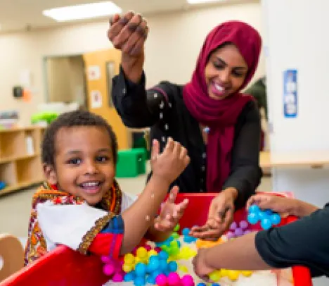 A mother playing with two children in a classroom