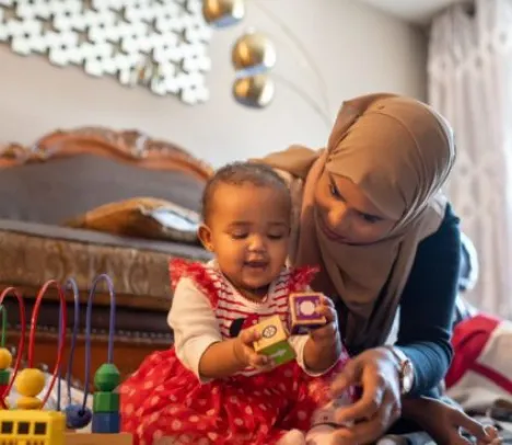 A mother playing with her child in a bedroom