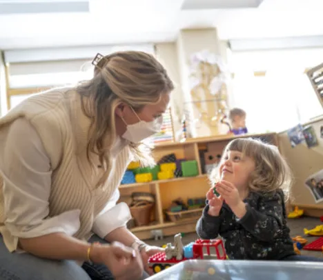 A woman in a mask interacting with a child