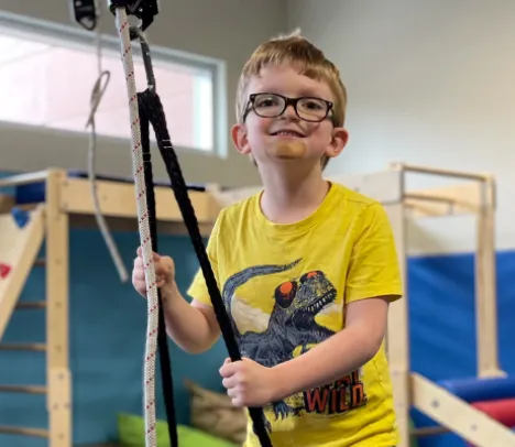 A smiling child holding a rope