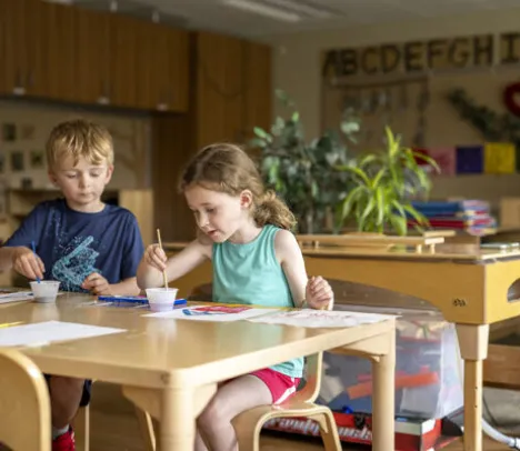 Two children doing art in a classroom