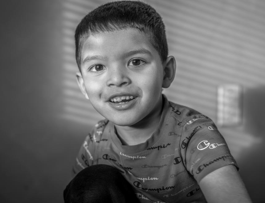 black and white image of a smiling young boy with short brown hair.