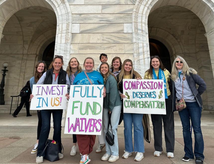 Group of Disability Services staff, holding signs in front of the St. Paul Capitol, advocating for waivered services. 