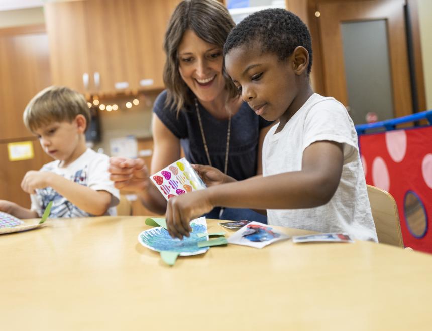 Therapist and two little boys work on a craft project at a table.