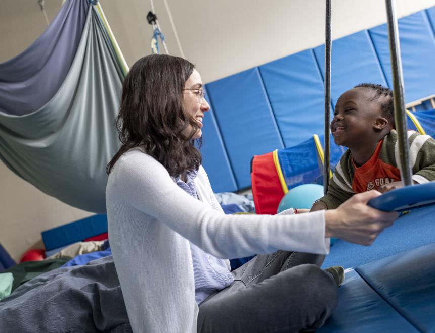 little boy on OT gym swing with clinician
