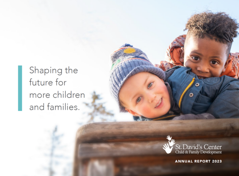 Two young boys playing outside with the title of the annual report spelled out next to them.