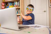 A child wearing glasses interacting with a laptop