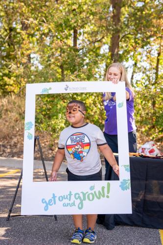A little boy wearing an animal mask taking a photo inside a giant picture frame