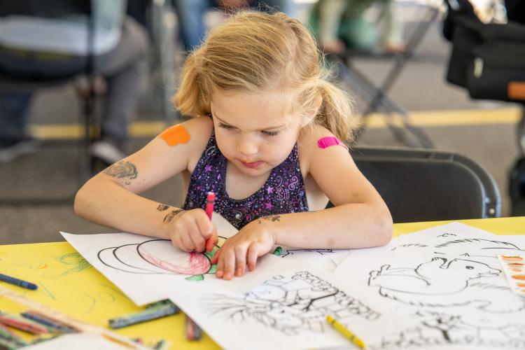 Little girl coloring at an outdoor event.