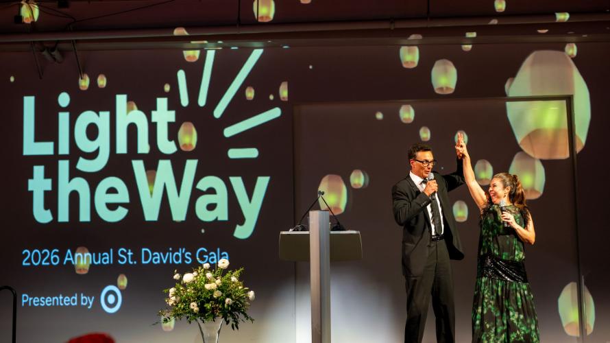 Photo of auctioneer and gala guest on stage at gala. 