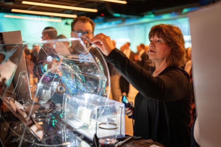 Woman drops raffle ticket into raffle drum at gala. 