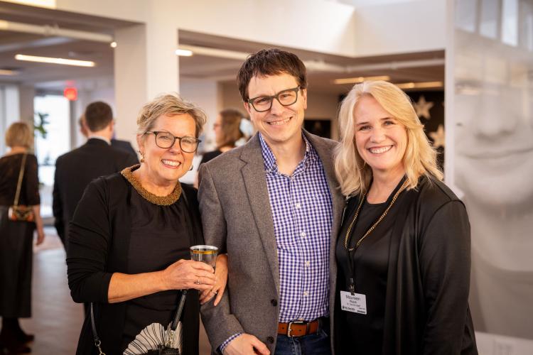 Group of people smiling at the camera in lobby of gala event.
