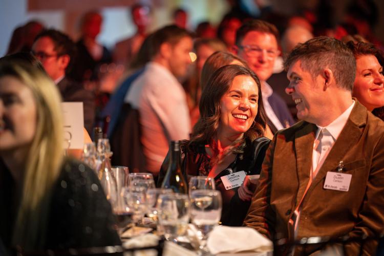 People at gala table laughing. 