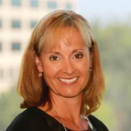 white woman with shoulder-length blond hair, smiling at the camera.