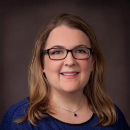 White woman with shoulder-length light brown hair and glasses, smiling.