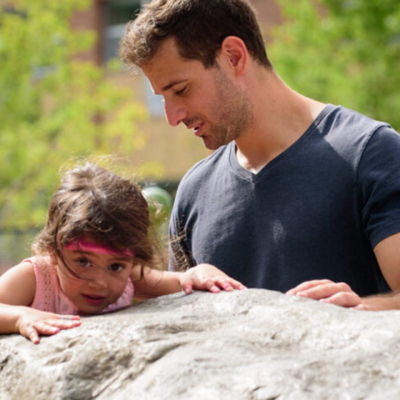 A parent next to a child on a rock