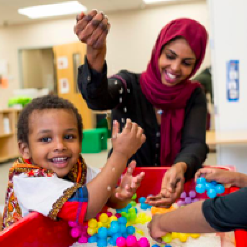 A mother playing with two children in a classroom