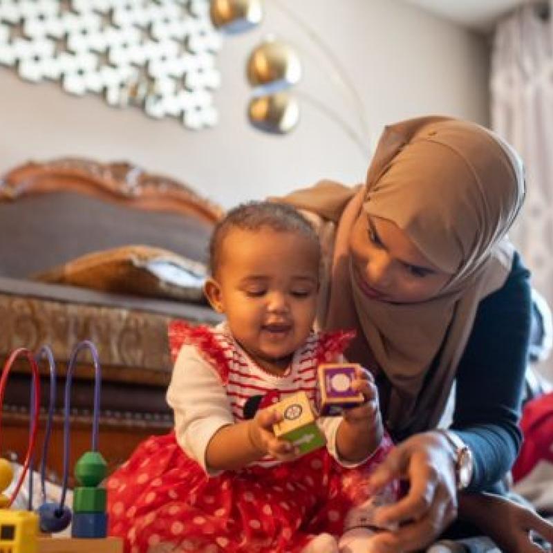A mother playing with her child in a bedroom