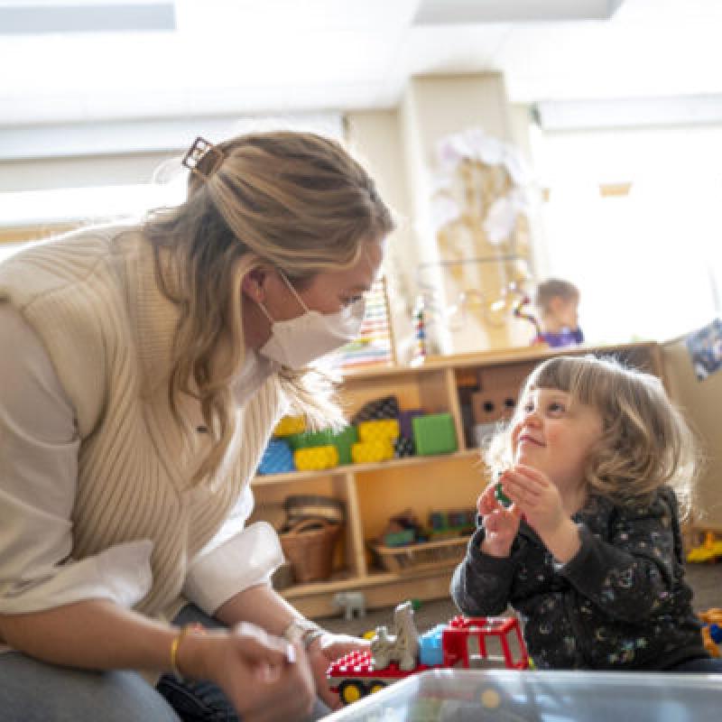 A woman in a mask interacting with a child