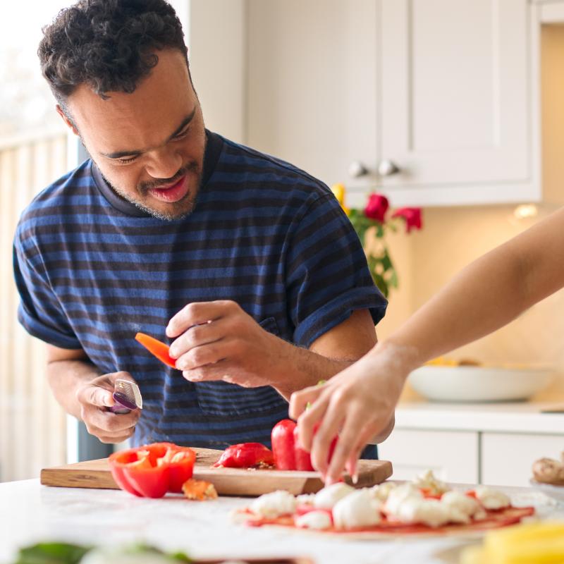 A caregiver and client cook together in the kitchen. 