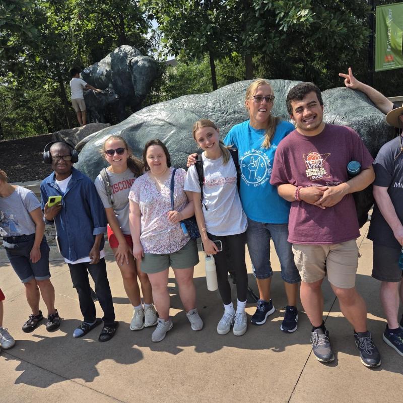 Group of young adults standing together in front of a buffalo statue