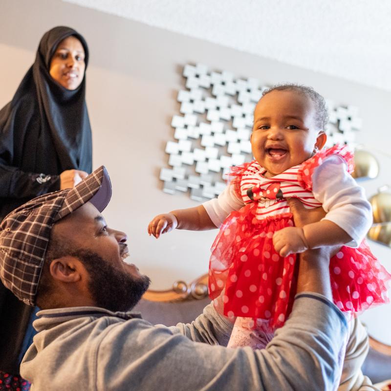 A Somali mother, father and baby girl playing in their living room.