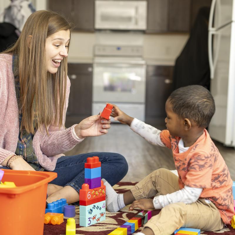 Female therapist and young boy playing together on the floor.