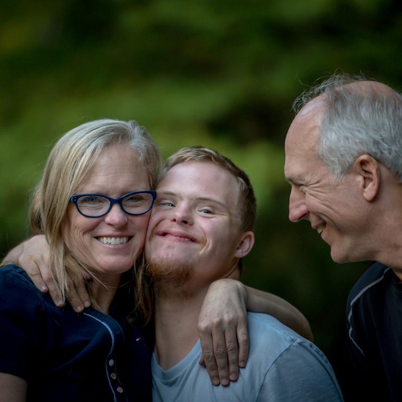 parents hugging young man with an intellectual disability