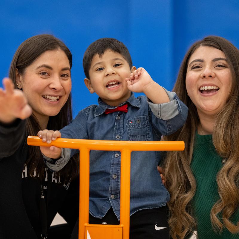 little latino boy on bike with his teachers